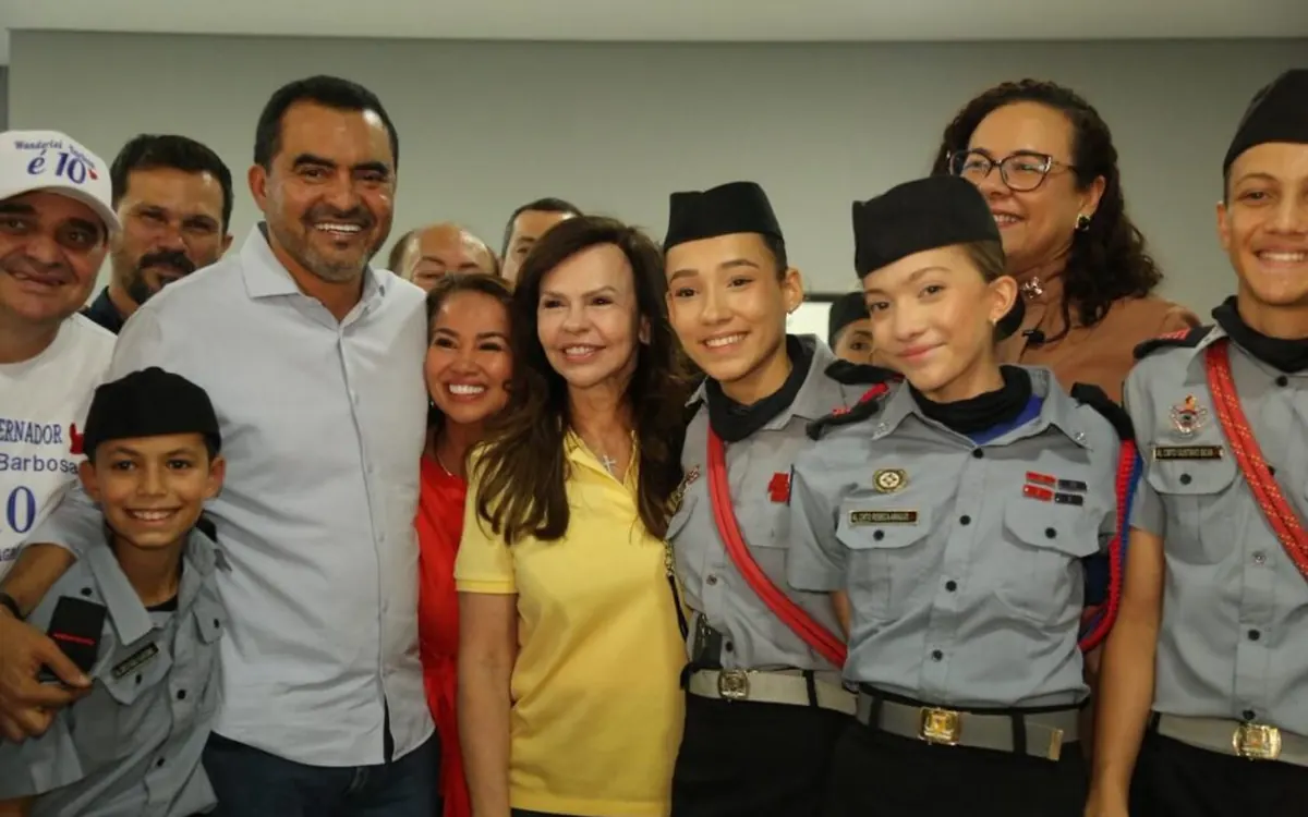 Professora Dorinha com alunos de uniforme escolar
